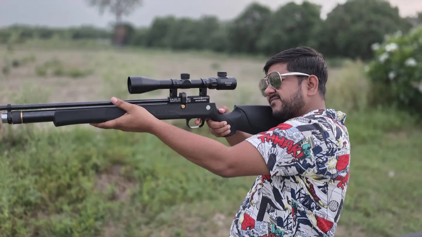 A shooter sighting down a scoped air rifle